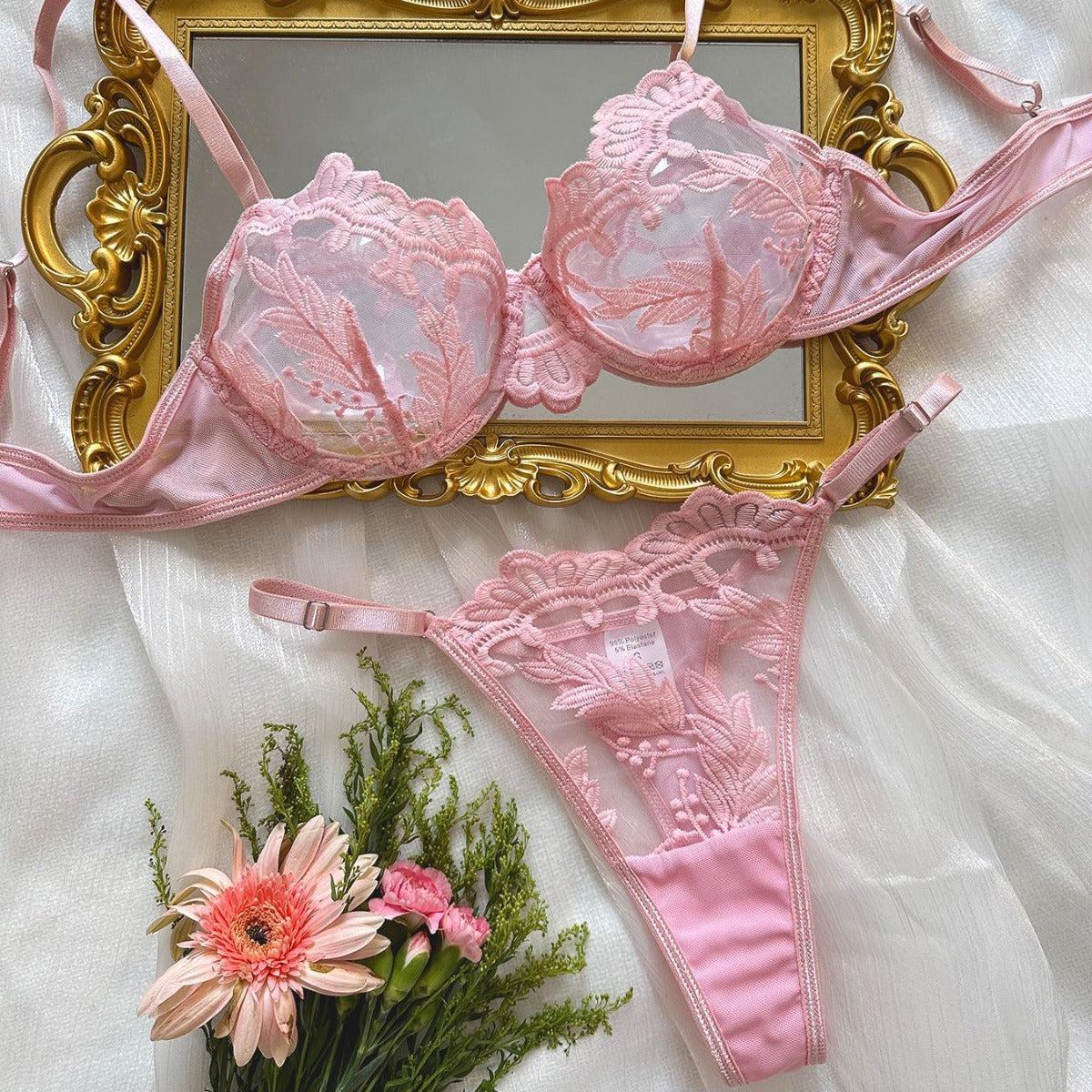 Pink women's embroidered mesh lace push-up lingerie set with bra and thong on a white fabric background with flowers and a decorative gold frame