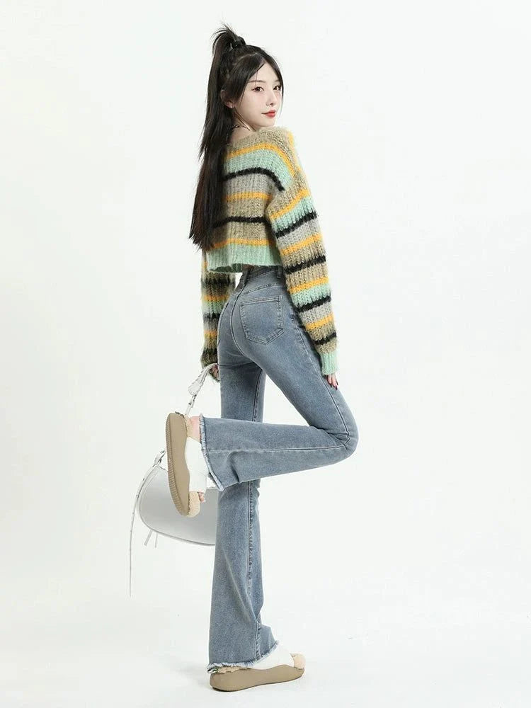 Retro high waist raw hem slightly flared jeans worn by a woman with a striped cropped sweater and beige shoes.