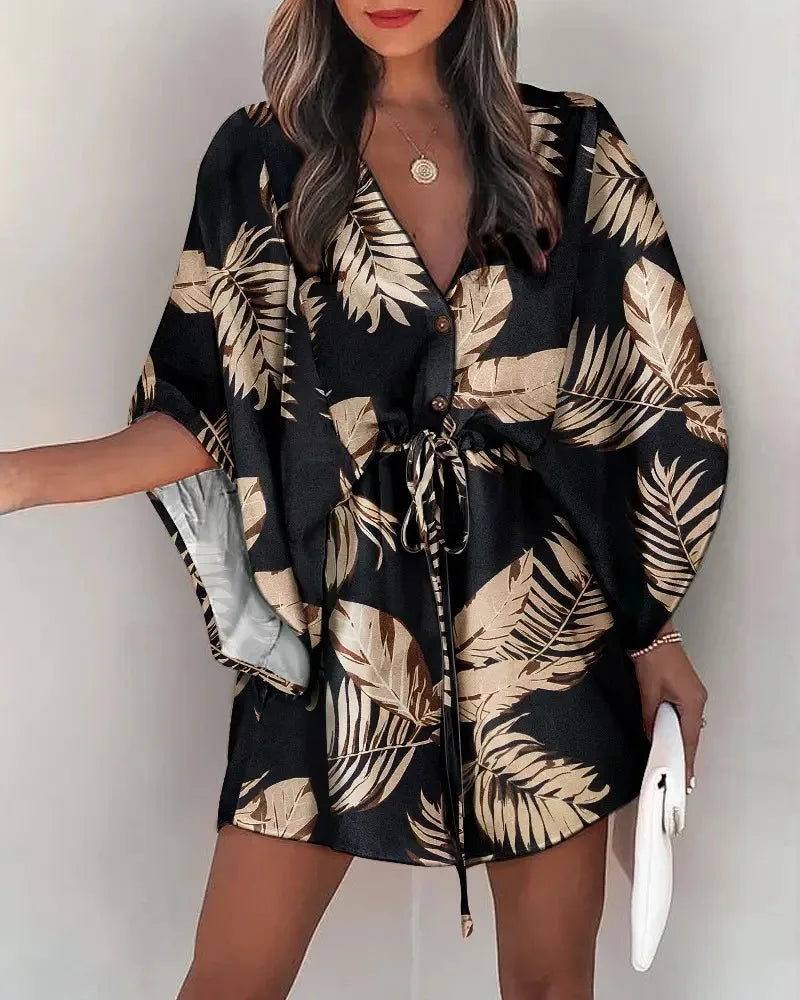 Woman wearing a Fashion Print V-Neck lace-up summer dress with tropical leaf patterns and flowy sleeves.