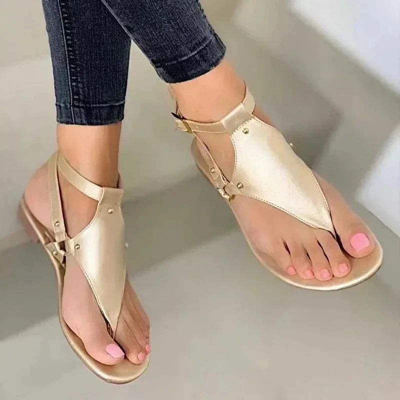 Women's fashion flip-flops in gold with gladiator design worn with jeans