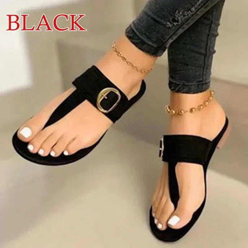 Black women's fashion flip-flops with gladiator design and buckle detail worn with ankle bracelets and black jeans