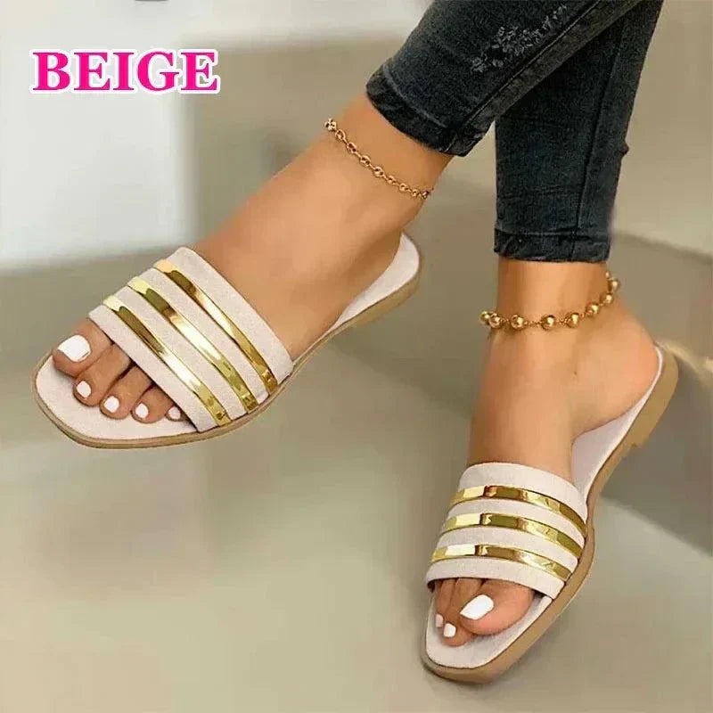 Beige women's fashion flip-flops with gold accents worn with black jeans and ankle bracelets