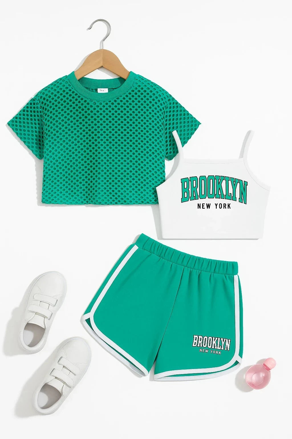 Girls' trendy 3-piece summer outfit set with green mesh t-shirt, white Brooklyn print tank top, green shorts, white sneakers, and pink water bottle on white background
