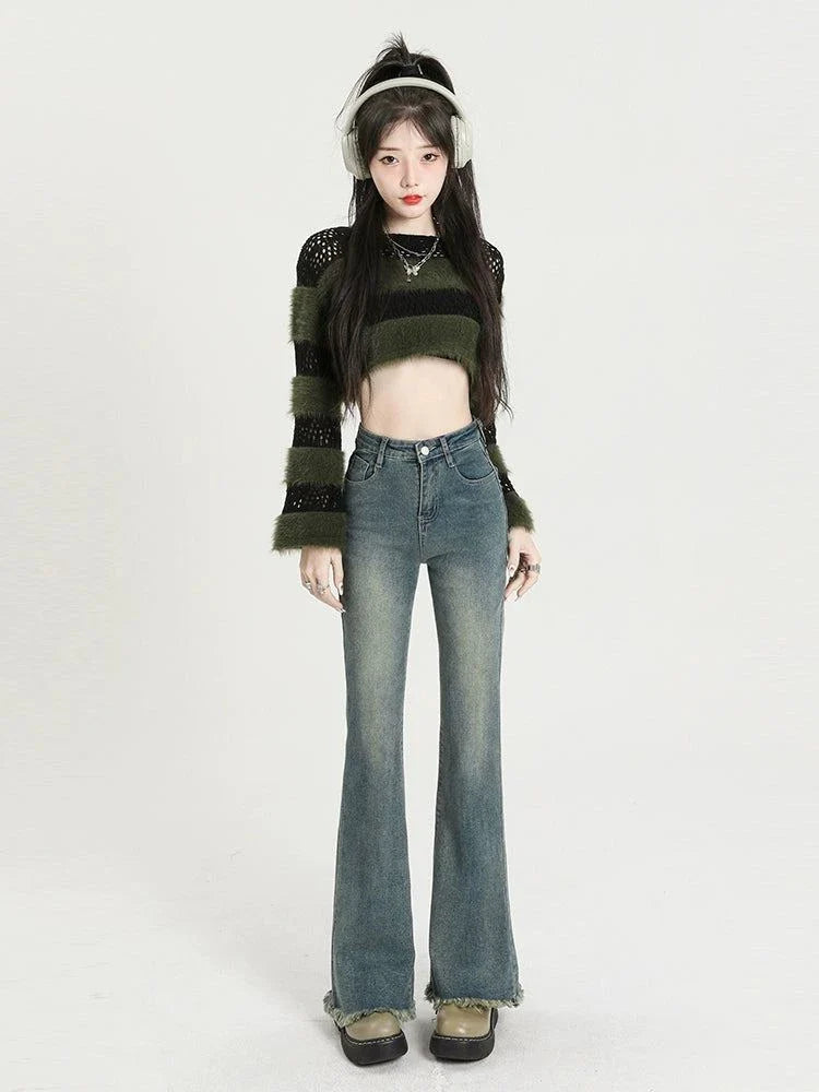 Retro high waist raw hem long slightly flared jeans worn by a model with a cropped striped sweater and headphones.