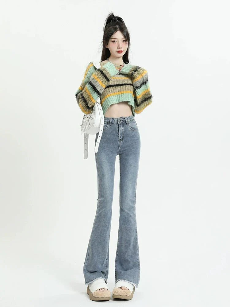 Retro high waist raw hem long slightly flared blue jeans worn by woman with cropped striped sweater and white sandals