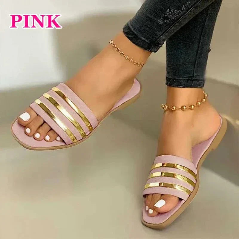 Pink women's fashion flip-flops with gold strap accents worn with anklets and dark jeans