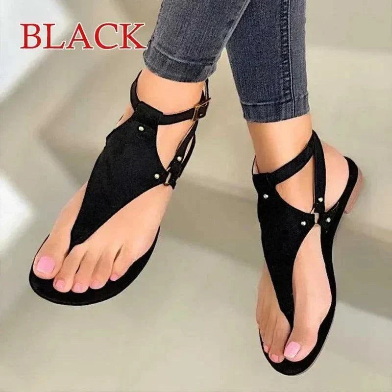 Black women's fashion flip-flops with gladiator design and ankle straps worn with jeans