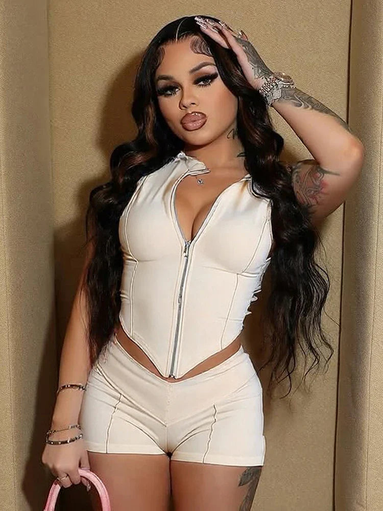 woman wearing sporty chic patchwork cream zip-up crop top and matching shorts set standing against beige wall