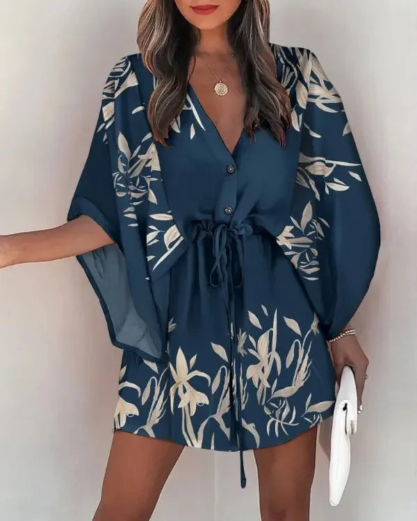 Woman wearing a navy blue fashion print V-neck lace-up summer dress with floral patterns, holding a white clutch.