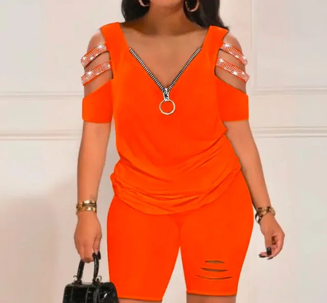 woman wearing bright orange summer casual hollow out 2-piece set with zip front top and fitted shorts holding black handbag