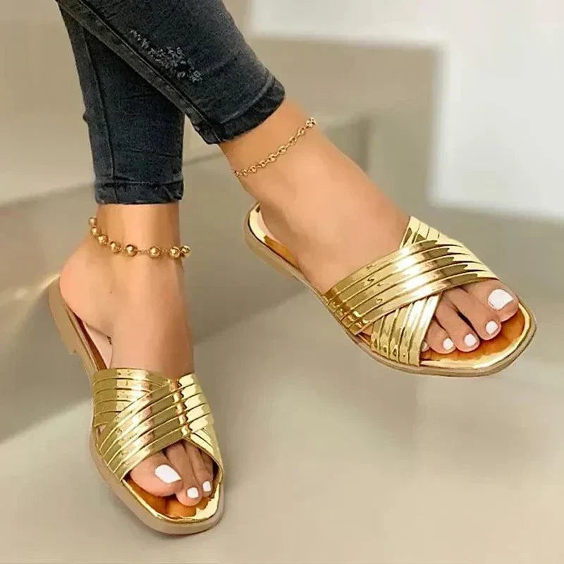 Women's gold gladiator-style fashion flip-flops for summer with ankle bracelets and white nail polish
