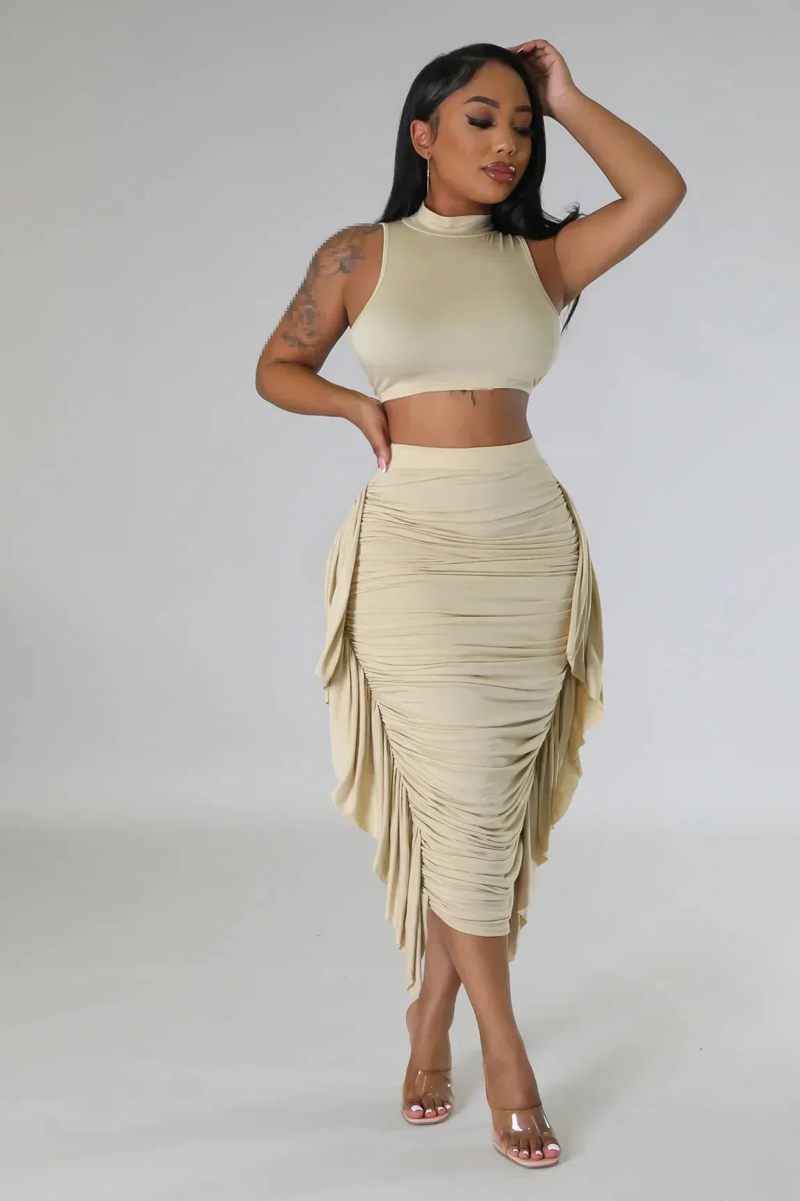 Woman wearing beige sleeveless crop top and ruched midi skirt from women's summer collection two-piece set