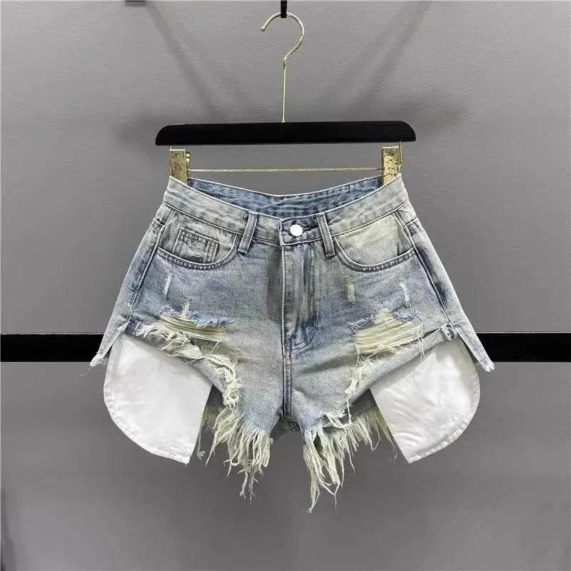 Korean high-waisted ripped denim shorts with patchwork and frayed hem hanging on black hanger against gray background