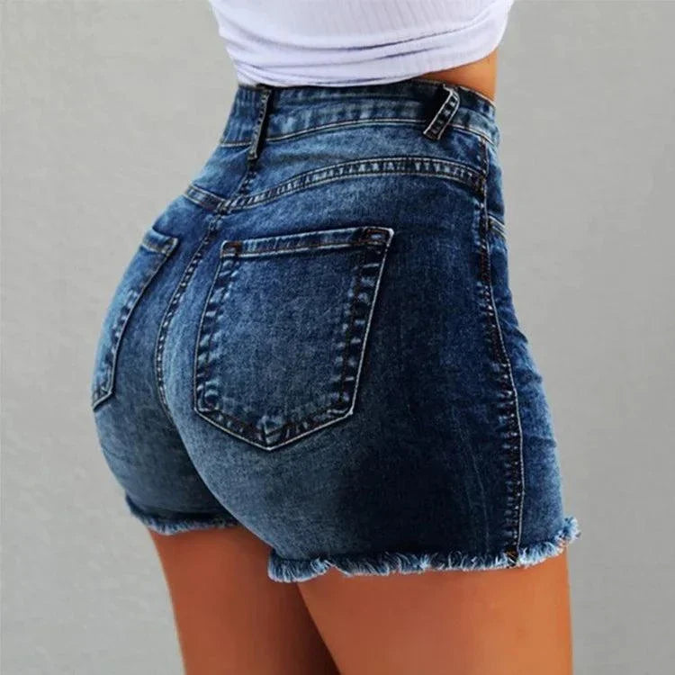 Close-up of woman wearing vintage distressed dark blue denim shorts with frayed hems and back pockets