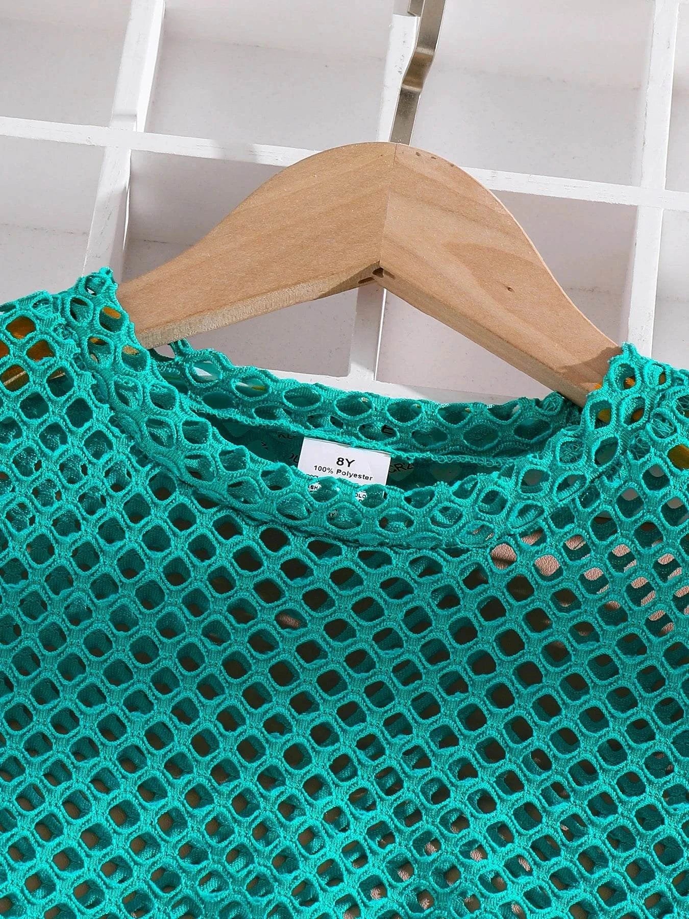 Close-up of girls' turquoise breathable mesh T-shirt on wooden hanger from trendy 3-piece summer outfit set