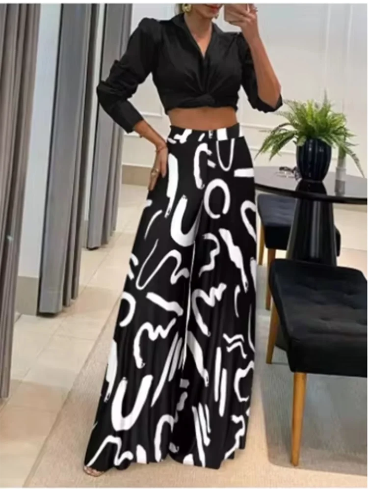 Woman wearing black and white geometric print wide leg pants paired with a black cropped blouse in a modern room setting