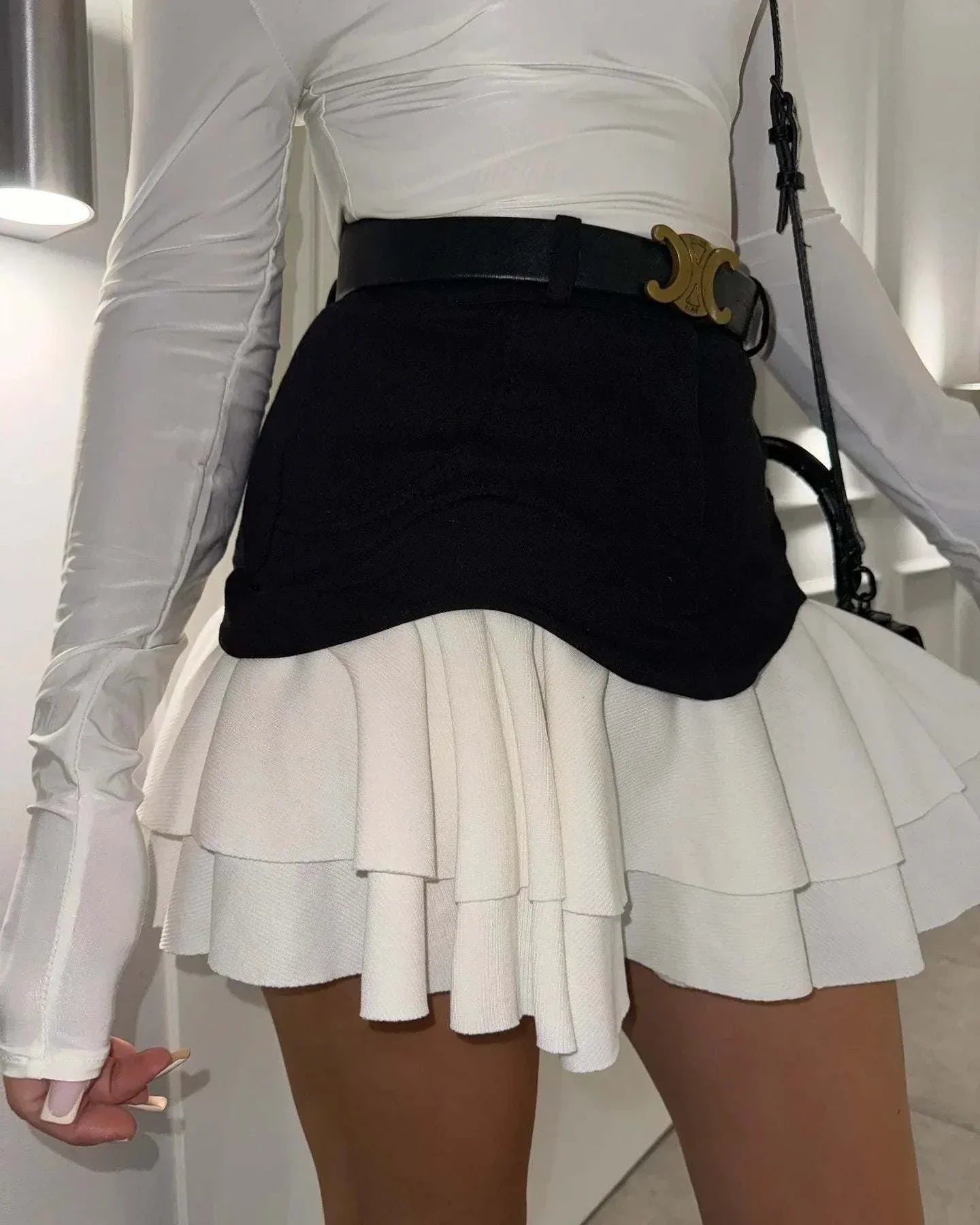 woman wearing high waist ruffle edge denim skirt with layered white ruffles and black belt