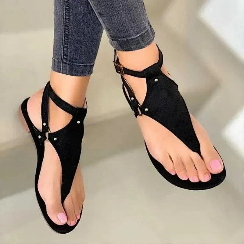 black women's fashion flip-flops with gladiator design worn with jeans on neutral background