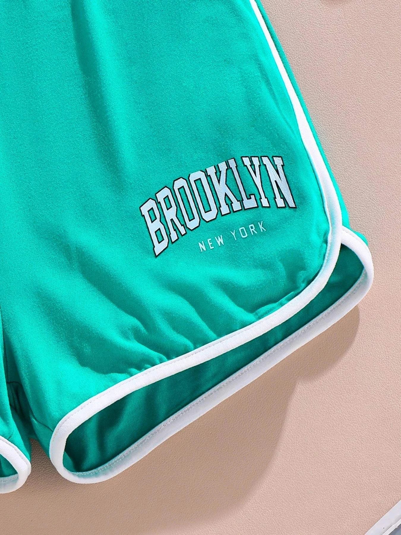 Close-up of teal girls' shorts with white trim and "Brooklyn New York" printed on the leg from a trendy 3-piece summer outfit set.
