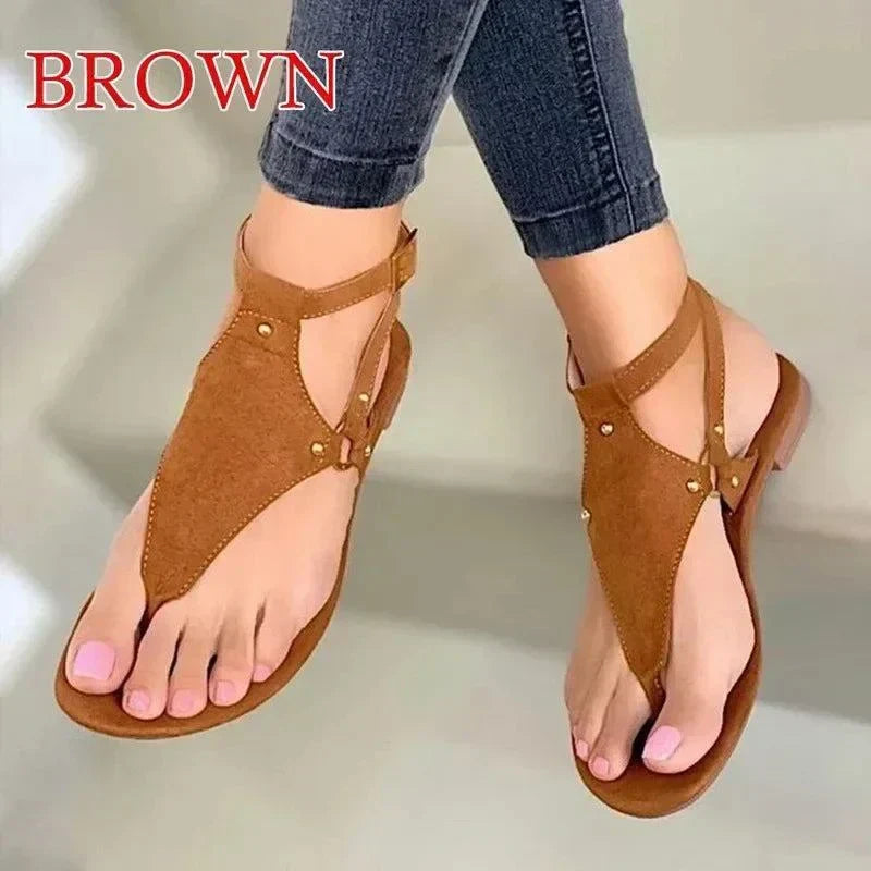 brown women's fashion flip-flops gladiator style summer sandals on feet with jeans
