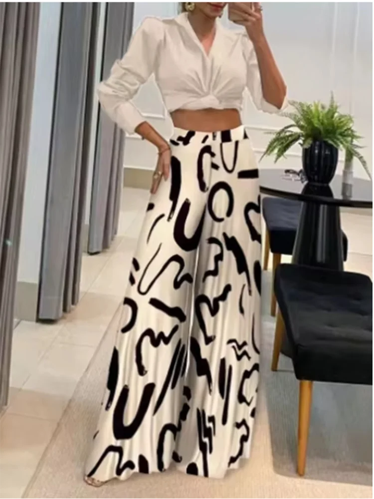 Woman wearing black and white geometric print wide leg pants with a white cropped blouse indoors