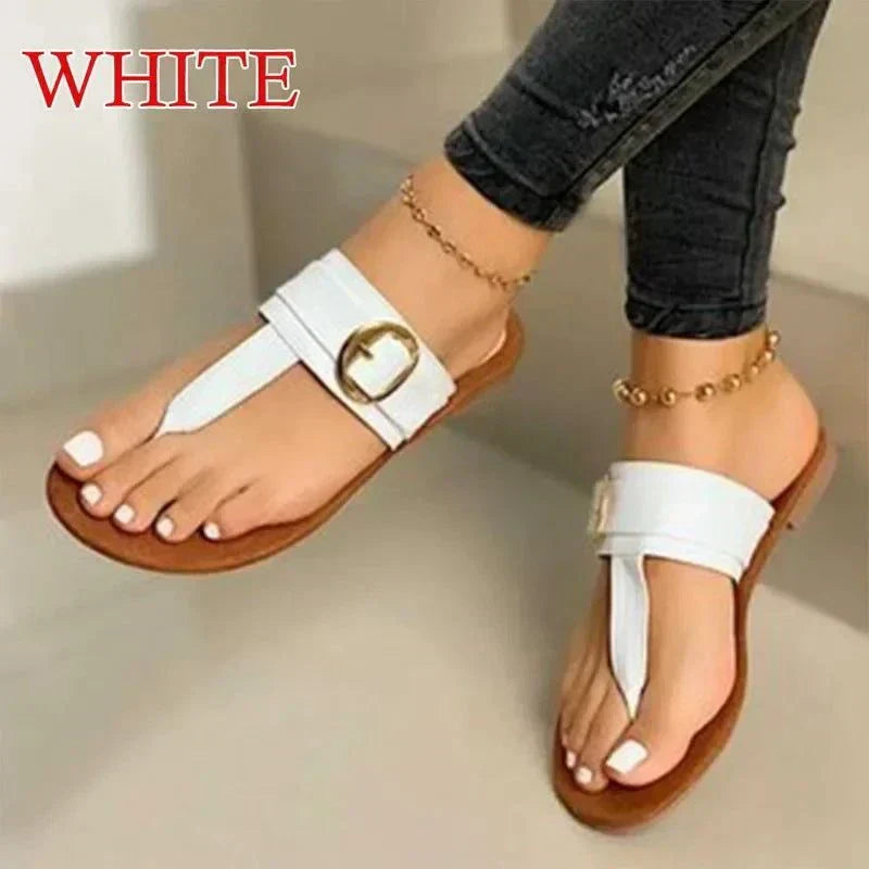 white women's fashion flip-flops with buckle detail on brown sole worn with ankle bracelets and black jeans
