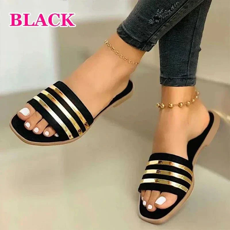 Black women's fashion flip-flops with gold striped gladiator design and cushioned insoles worn with ankle bracelets.