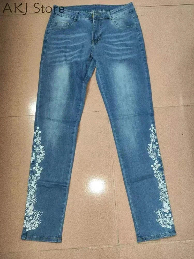 Blue women's skinny jeans with white floral embroidery along the lower legs