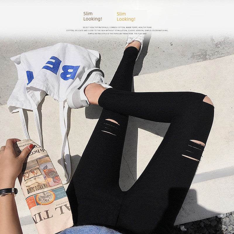 Woman wearing black ripped leggings with white sneakers, holding a newspaper and a white tote bag on the ground outdoors