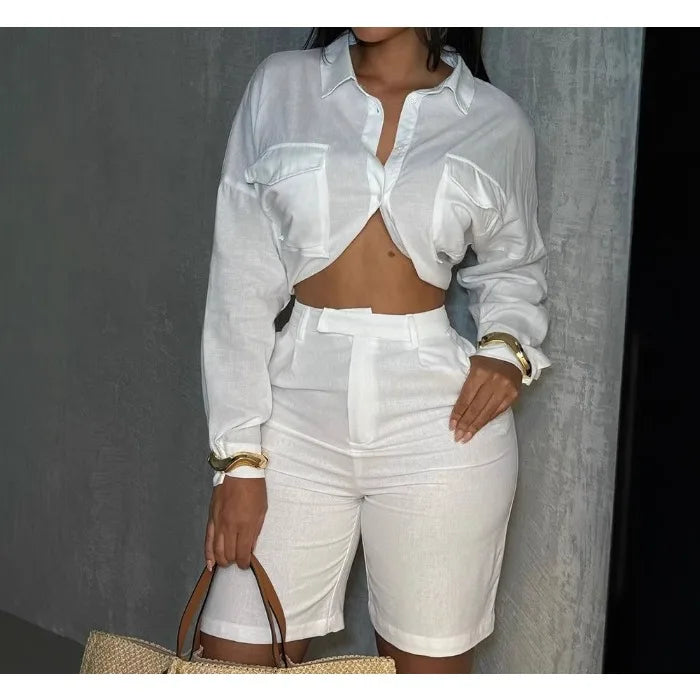 Woman wearing a white breathable summer two-piece set with long-sleeve cropped shirt and high-waisted shorts, styled for casual chic look